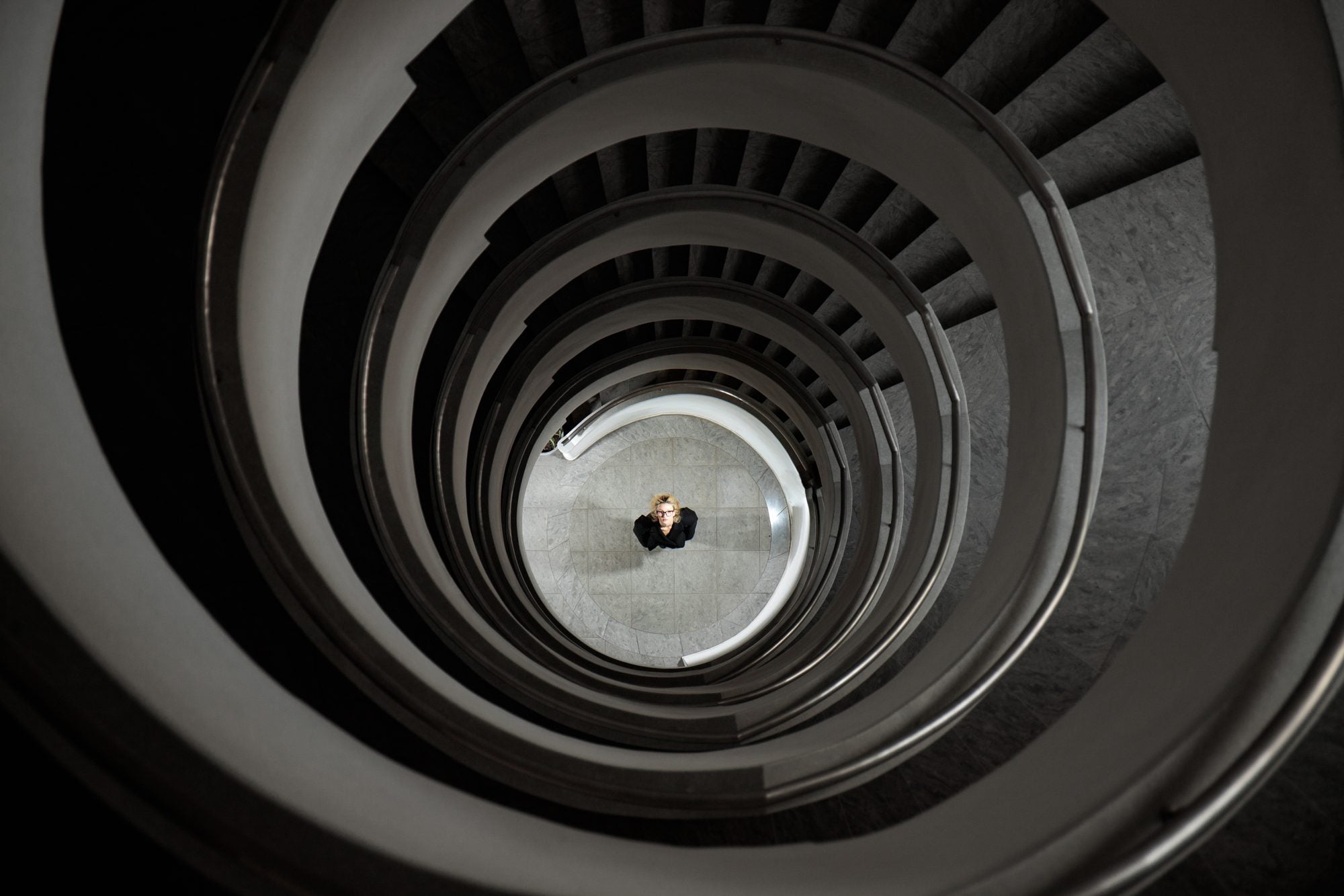 A figure at the bottom of a spiral staircase, seen from above